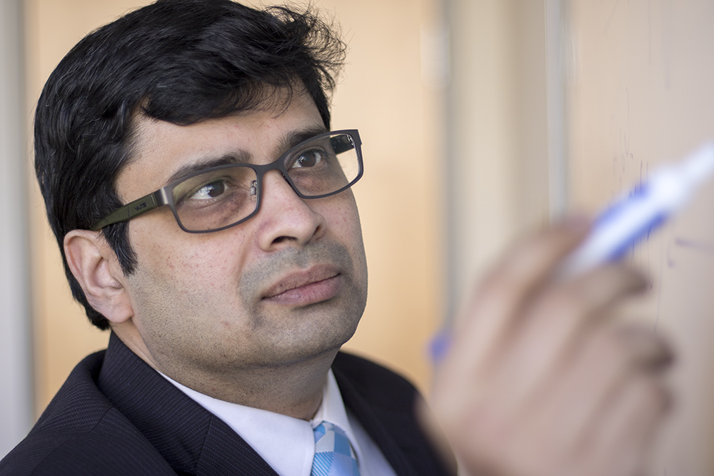 Professor Sri Krishnan writes on a whiteboard with a blue marker.